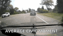 a car is driving down a road with a truck behind it and the words `` average civic moment '' on the dashboard .
