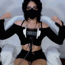 a woman wearing headphones and a mask flexes her muscles