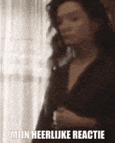 a blurry picture of a woman standing in front of a window with the words mijn heerlijke reactie written below her .