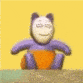 a purple teddy bear with a white face is sitting on a yellow background