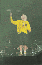 a woman wearing a yellow sweater that says " i 'm american " stands on stage