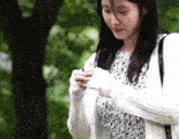 a woman in a white sweater is holding a flower