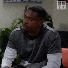 a man sitting on a couch with a bet logo on the corner