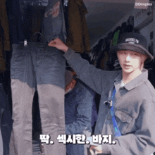 a man wearing a bucket hat holds a pair of pants