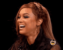 a woman with braided hair is smiling and wearing a black shirt with a shark on it