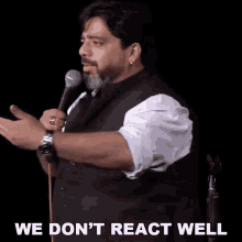 a man speaking into a microphone with the words " we don 't react well " written below him