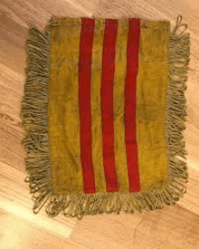 a yellow and red striped pillow with fringe is sitting on a wooden table .