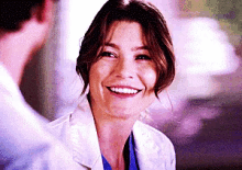 a woman in a lab coat is smiling and looking at the camera