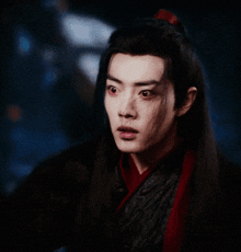 a man with long hair and a red scarf around his neck