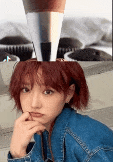 a girl with red hair is standing in front of a cupcake