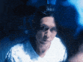 a man in a hospital gown looks at the camera in a dark room