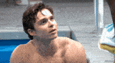 a shirtless man in a pool with a towel behind him