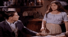 a man and a woman are standing next to each other at a table .