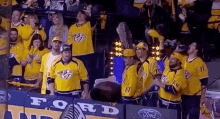 a group of people wearing yellow jerseys are standing in a stadium .