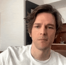 a man with brown hair is wearing a white t-shirt .