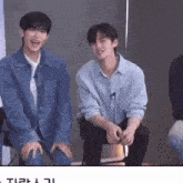 two men are sitting next to each other and one of them is wearing a blue shirt