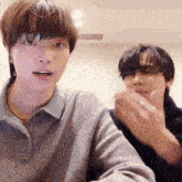 two young men are sitting next to each other and one of them is wearing a ring on his finger