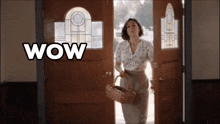 a woman is holding a basket in front of a door that says wow on it