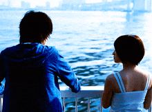 a man and a woman are looking out over the water