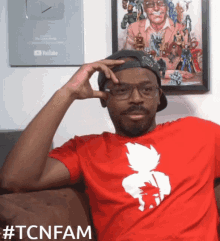 a man wearing a red shirt that says tcnfam on it