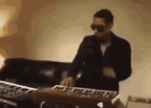 a man in sunglasses is playing a keyboard in a room .