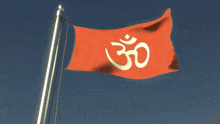 a red flag with an om symbol on it is flying in the wind