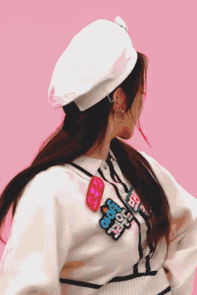 a woman wearing a white beret and a white sweater has a patch on her sweater that says beach