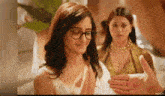 a woman wearing glasses is clapping her hands in front of a man