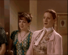 two women are standing next to each other in a room
