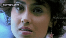 a close up of a woman 's face with curly hair and earrings .