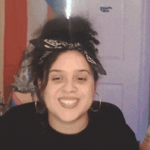 a woman with a bandana on her head smiles for the camera