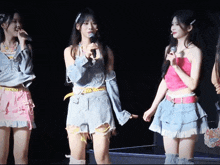 a girl in a pink top is holding a microphone while standing next to two other girls