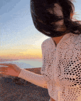 a woman with her hair blowing in the wind in front of a sunset