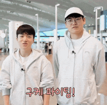 two men standing next to each other wearing hoodies and a hat with korean writing on them