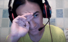 a man wearing headphones and a microphone wipes his eyes with his hand