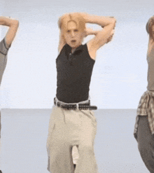 a man in a black shirt and khaki pants is dancing with his hands behind his head