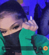 a woman wearing a green jacket and a black mask is holding a pen .