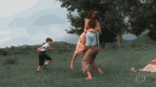 a man is carrying a woman on his shoulders while a boy runs in the grass