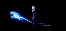 a woman in a black dress is standing in a dark room surrounded by purple and blue lights .