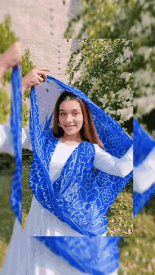 a woman wearing a white dress and a blue scarf around her head .