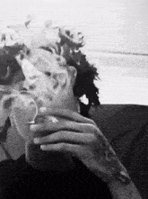 a person with a tattoo on their hand is smoking a cigarette