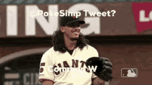 a baseball player with long hair is smiling in front of a sign that says poke simp tweet ?