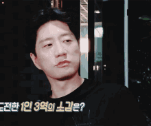 a man in a black shirt with korean writing on the bottom right