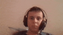 a young man wearing headphones and a microphone is holding a remote control .