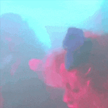 a person in a pink shirt is standing in a room with smoke coming out of it .