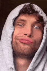 a man with a beard wearing a hoodie making a funny face