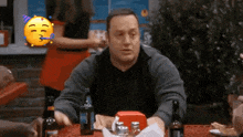 a man is sitting at a table with bottles of beer and a sandwich .