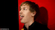 a young man is sticking his tongue out against a red background .