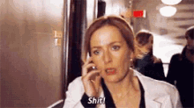 a woman is talking on a cell phone in a hallway and saying `` shit ! ''