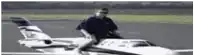 a man is sitting on the back of a small airplane .